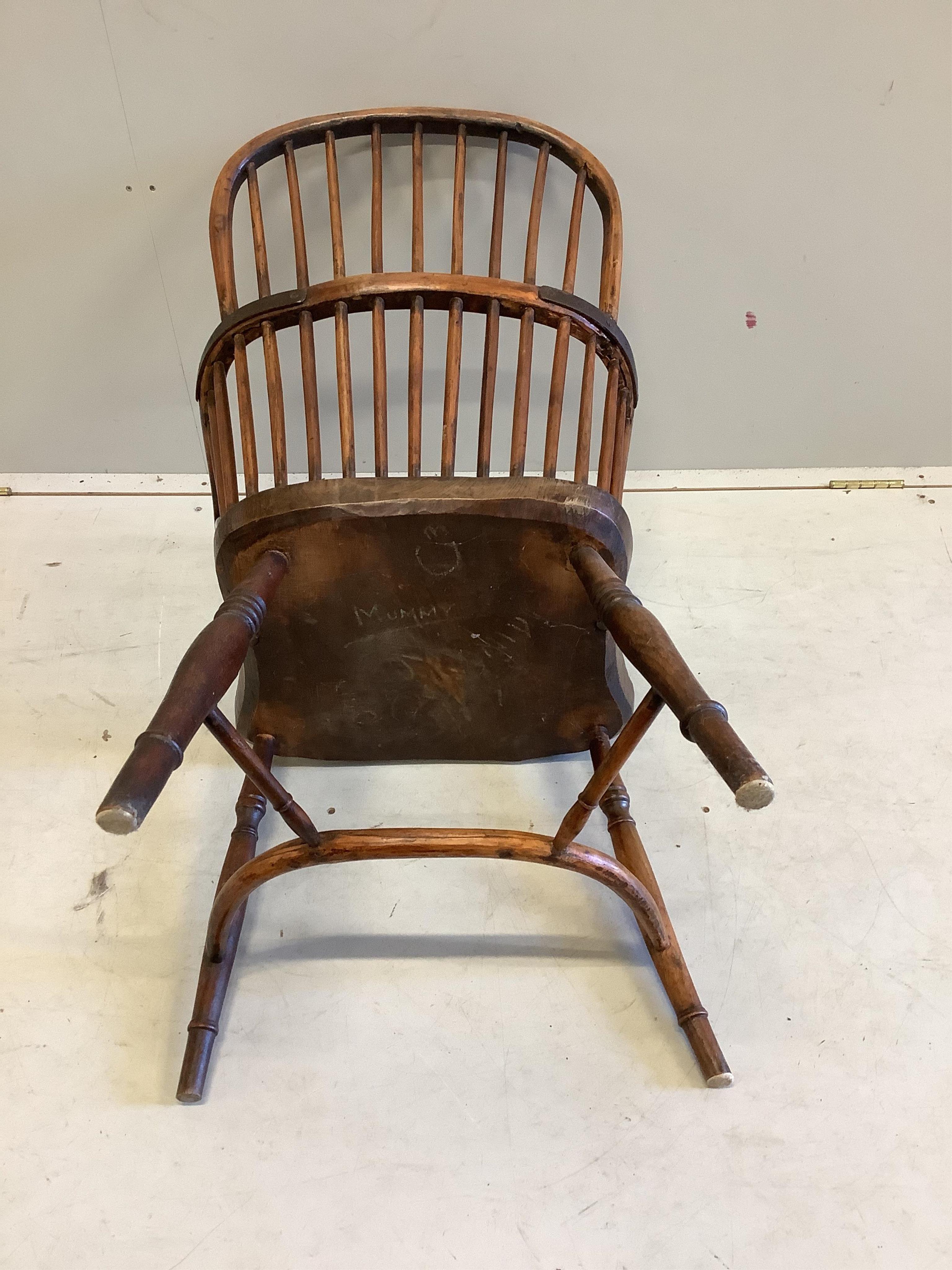 An early 19th century yew and elm comb back Windsor elbow chair with crinoline stretcher, width 53cm, depth 42cm, height 99cm. Condition fair, arm rail split to left side, left leg now misshapen with minor chips.